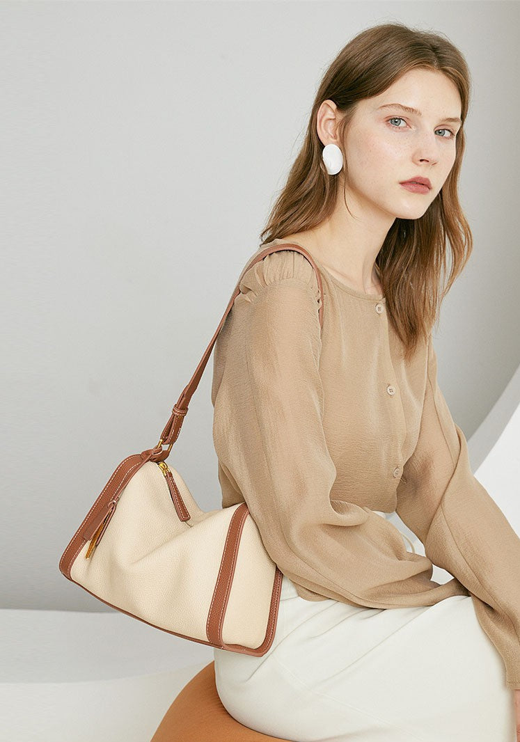 The two - tone brown - beige hobo shoulder bag has a minimalist design.
