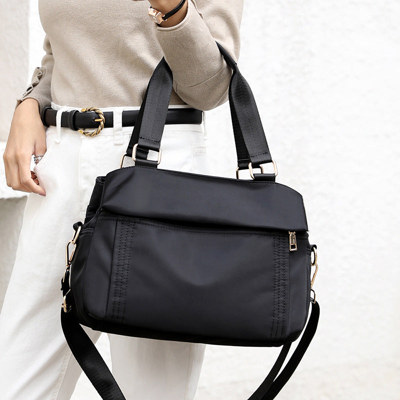 The black tote handbag can be carried by hand, crossbody or on the shoulder.